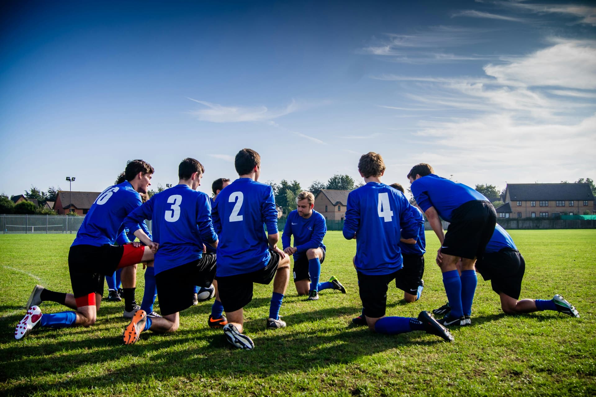 image of a team of football players planning together while kneeling on the grass